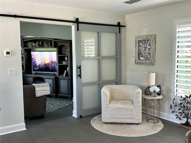 living area with a barn door and a textured ceiling