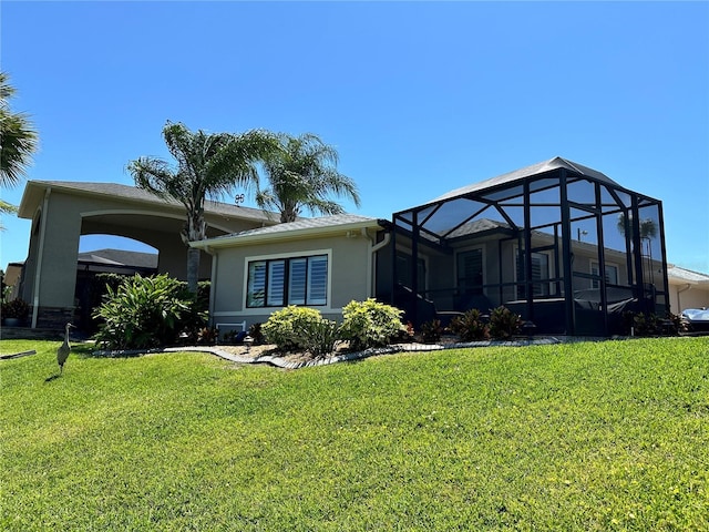 back of property featuring glass enclosure and a yard