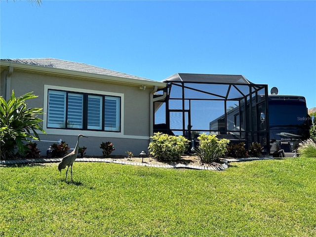 rear view of property featuring stucco siding, a lanai, and a lawn