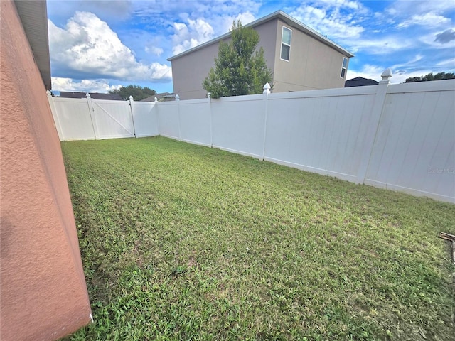 view of yard with a fenced backyard and a gate