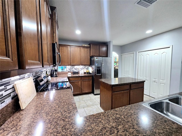 kitchen with tasteful backsplash, sink, stainless steel appliances, and a kitchen island