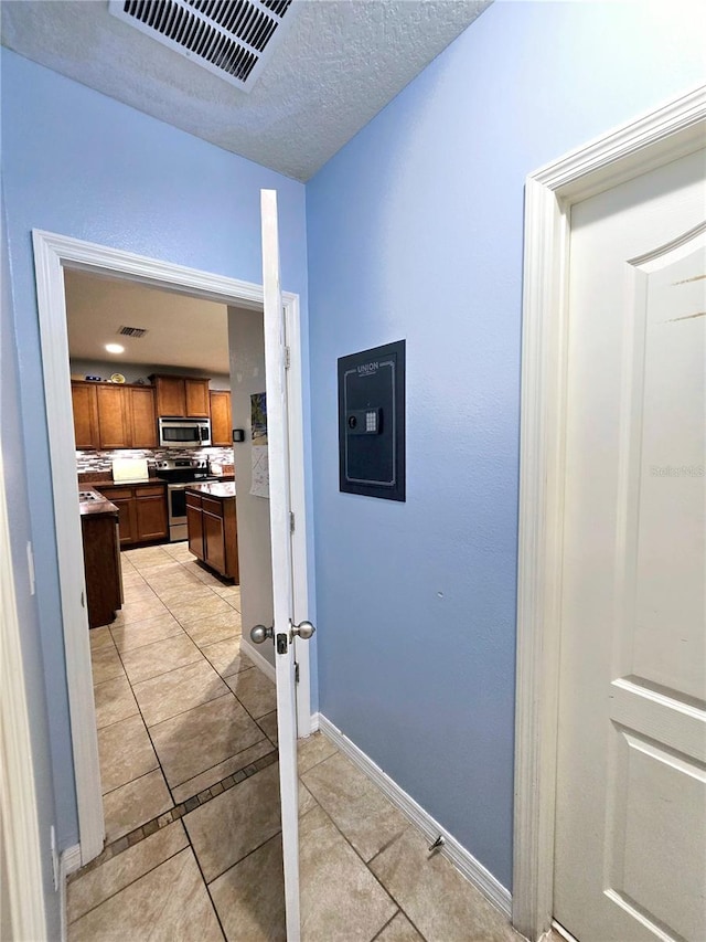 corridor featuring a textured ceiling and light tile patterned flooring