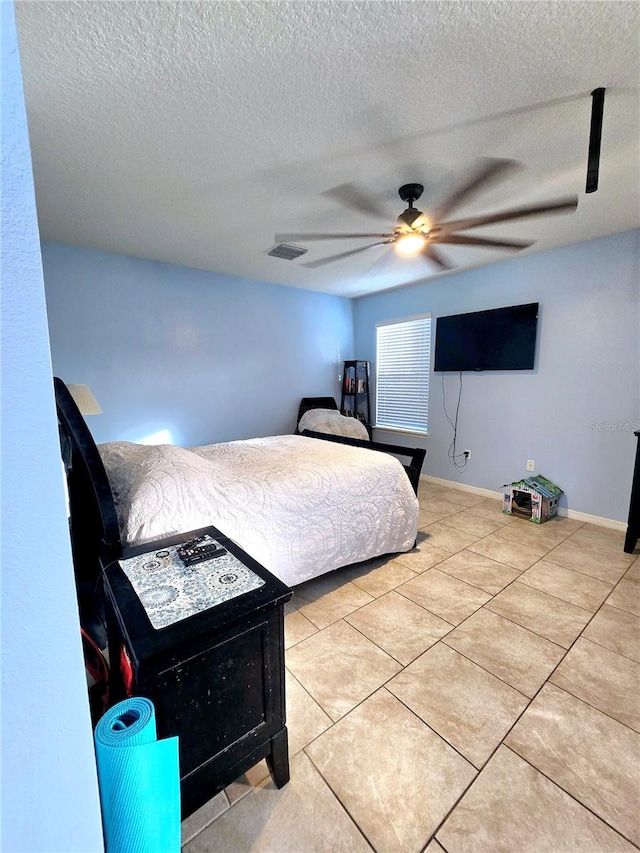 tiled bedroom with a textured ceiling and ceiling fan