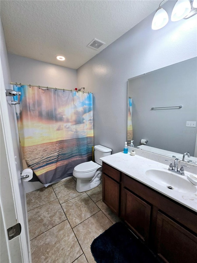 bathroom with tile patterned flooring, vanity, a textured ceiling, and toilet