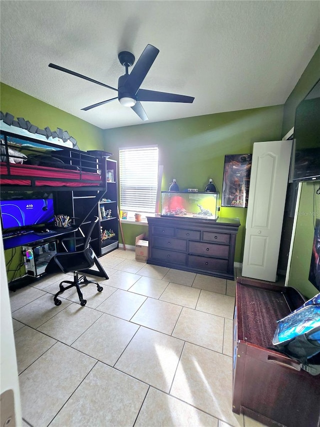 bedroom with ceiling fan, light tile patterned floors, and a textured ceiling