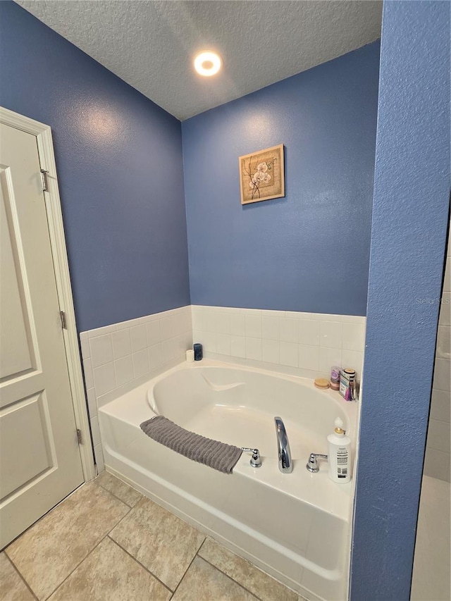 bathroom with a bathtub, tile patterned floors, and a textured ceiling