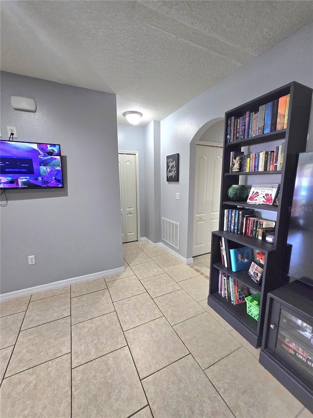 corridor with light tile patterned flooring and a textured ceiling