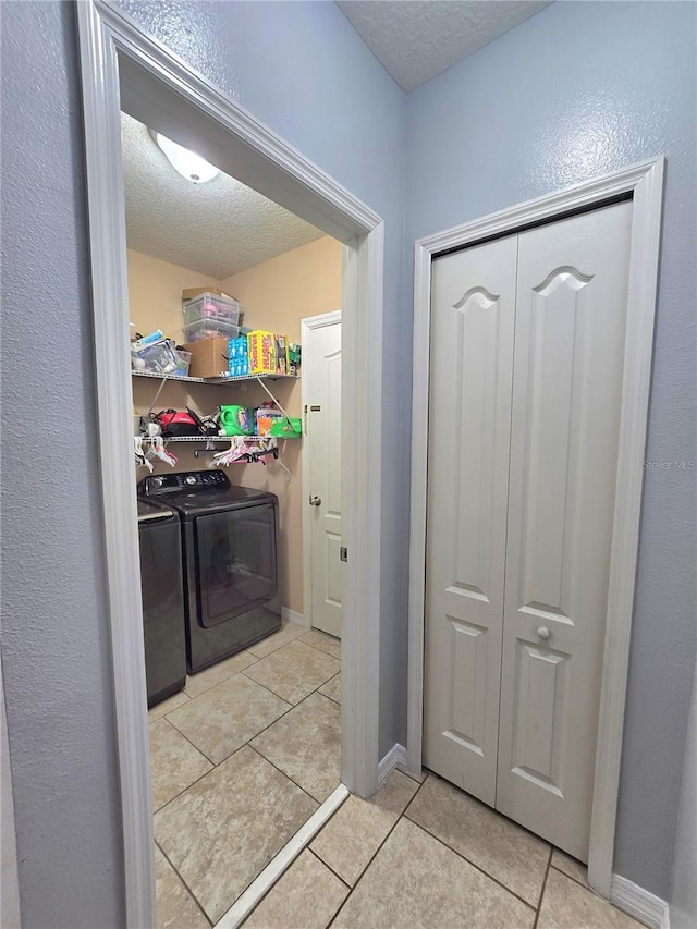 washroom with separate washer and dryer, light tile patterned floors, and a textured ceiling