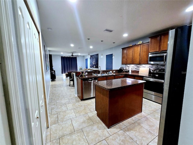 kitchen with sink, stainless steel appliances, a center island, decorative light fixtures, and kitchen peninsula