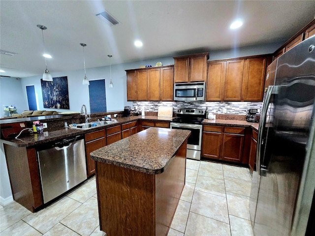 kitchen featuring sink, decorative light fixtures, appliances with stainless steel finishes, kitchen peninsula, and a kitchen island