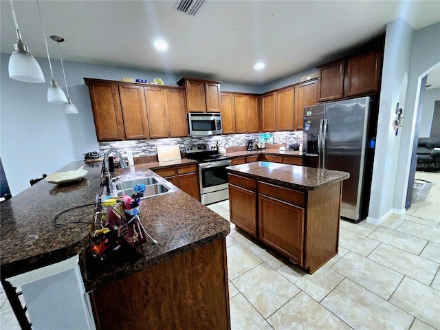 kitchen featuring pendant lighting, sink, stainless steel appliances, tasteful backsplash, and kitchen peninsula