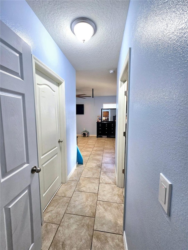 hall featuring a textured ceiling and light tile patterned floors