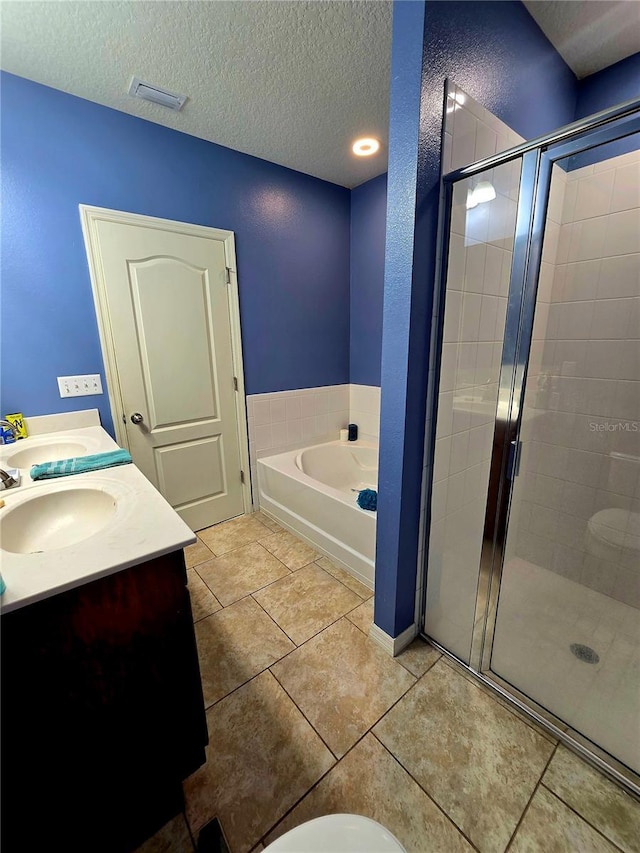 bathroom with tile patterned floors, separate shower and tub, a textured ceiling, and vanity