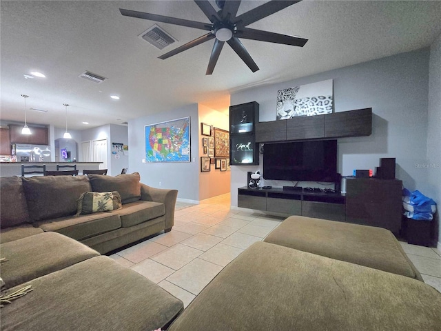 tiled living room with ceiling fan and a textured ceiling