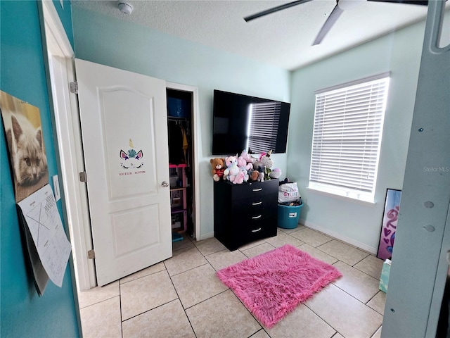 tiled bedroom with ceiling fan, a closet, and a textured ceiling