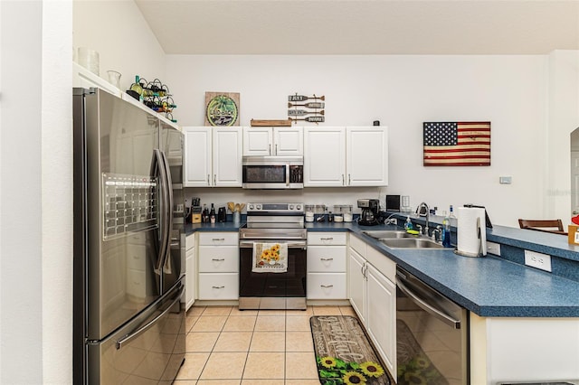 kitchen with appliances with stainless steel finishes, light tile patterned flooring, sink, and white cabinets