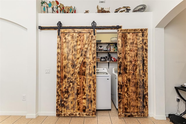 washroom featuring a barn door, light tile patterned floors, and washing machine and clothes dryer