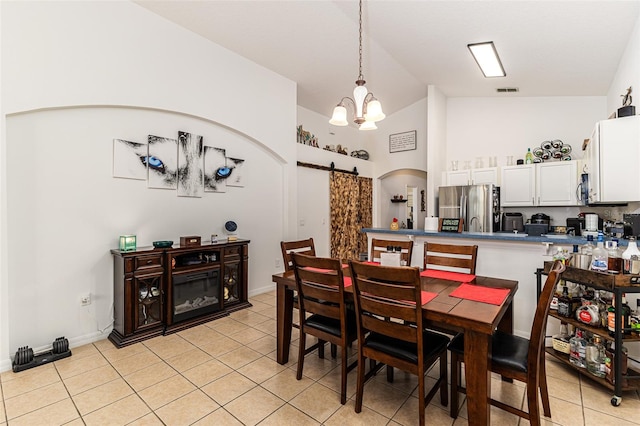 tiled dining area featuring a notable chandelier, high vaulted ceiling, and a barn door