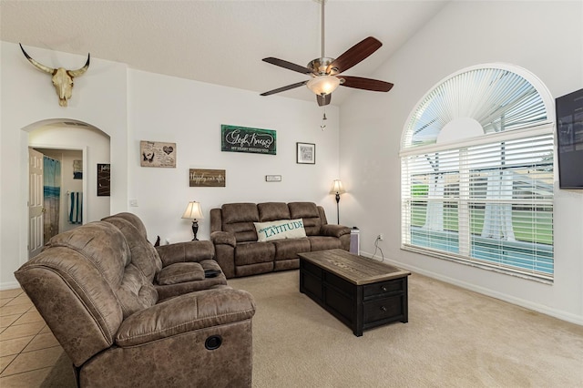 tiled living room with ceiling fan and high vaulted ceiling