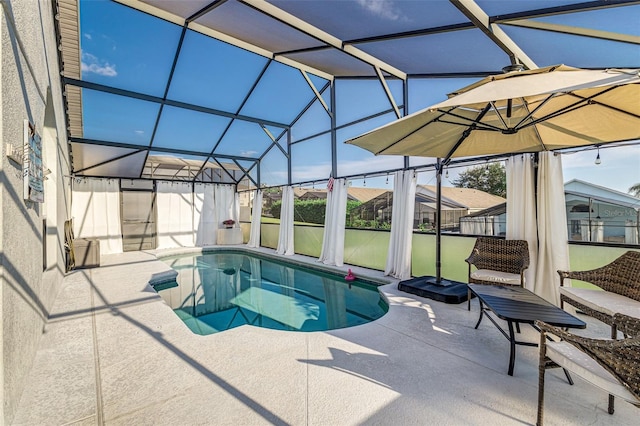 view of pool with glass enclosure and a patio area