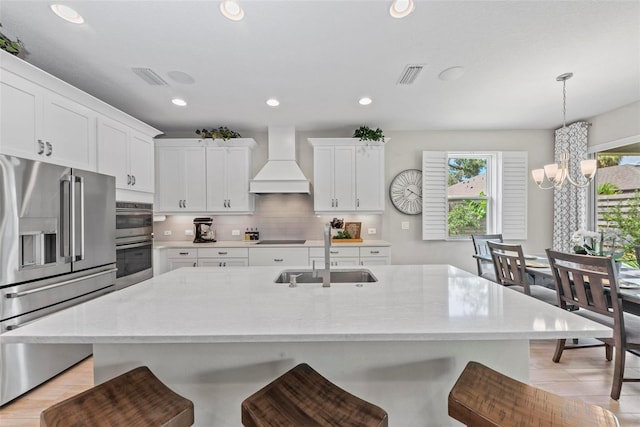 kitchen featuring premium range hood, sink, a chandelier, white cabinetry, and appliances with stainless steel finishes