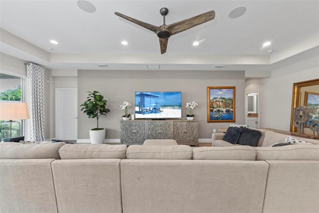 living room featuring ceiling fan and a tray ceiling