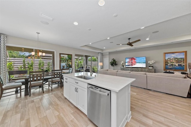 kitchen featuring an island with sink, white cabinets, ceiling fan with notable chandelier, stainless steel dishwasher, and sink