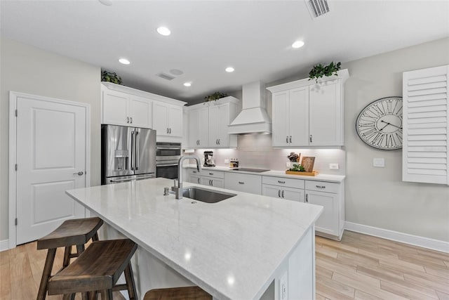 kitchen with stainless steel appliances, white cabinetry, custom range hood, and sink