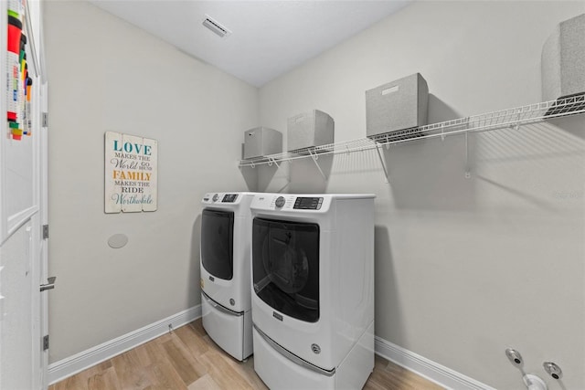 laundry room with separate washer and dryer and hardwood / wood-style floors