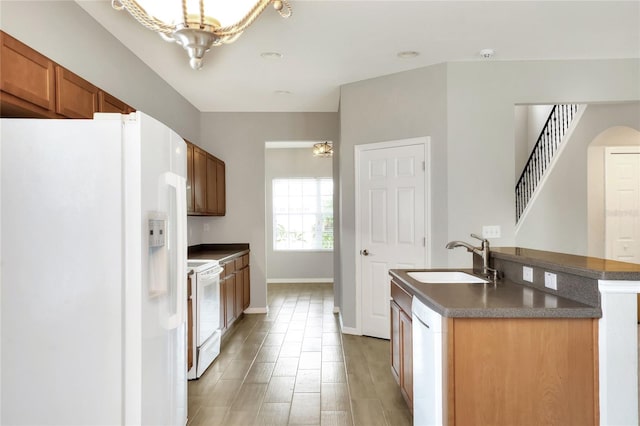 kitchen featuring wood-type flooring, a kitchen island with sink, sink, an inviting chandelier, and white appliances