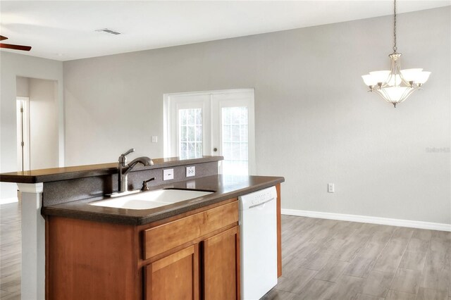 kitchen featuring hanging light fixtures, ceiling fan with notable chandelier, dishwasher, a center island with sink, and sink