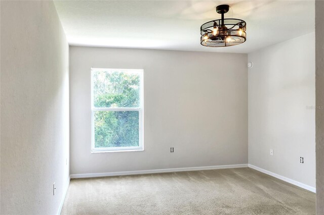 carpeted spare room with a notable chandelier