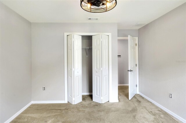 unfurnished bedroom featuring light colored carpet and a closet