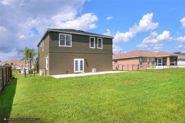 rear view of property with french doors, a lawn, and a patio