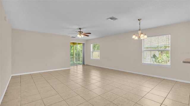 tiled spare room with ceiling fan with notable chandelier