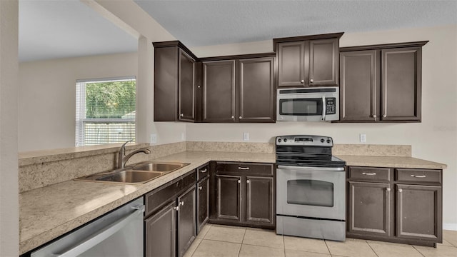 kitchen with dark brown cabinetry, light tile patterned flooring, appliances with stainless steel finishes, and sink