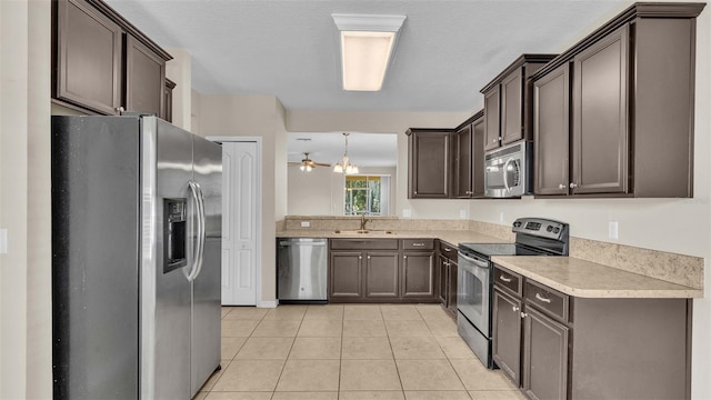 kitchen with dark brown cabinets, sink, stainless steel appliances, light tile patterned floors, and ceiling fan