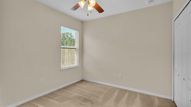 unfurnished bedroom with a closet, multiple windows, light colored carpet, and ceiling fan