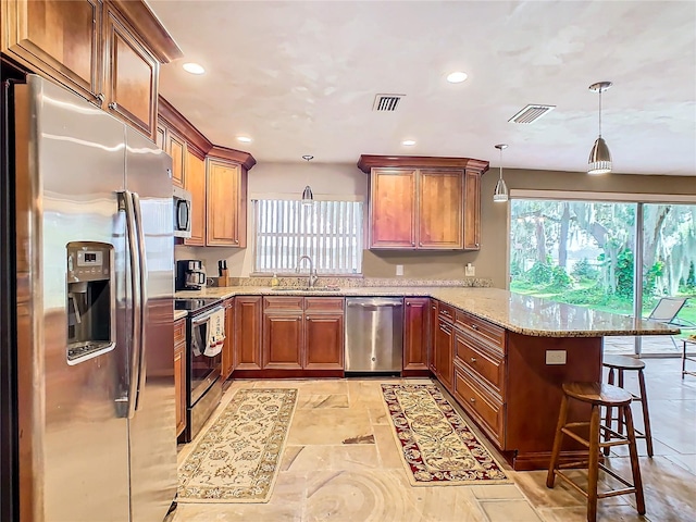 kitchen featuring plenty of natural light, appliances with stainless steel finishes, decorative light fixtures, a kitchen bar, and kitchen peninsula