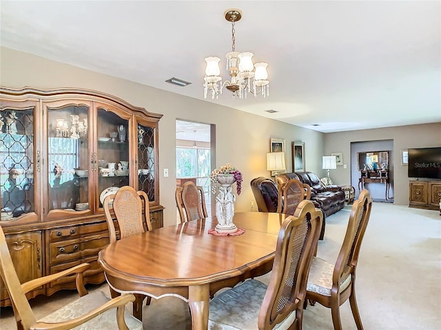 dining space with a notable chandelier and light carpet