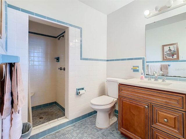 bathroom with tile patterned floors, a tile shower, vanity, tile walls, and toilet