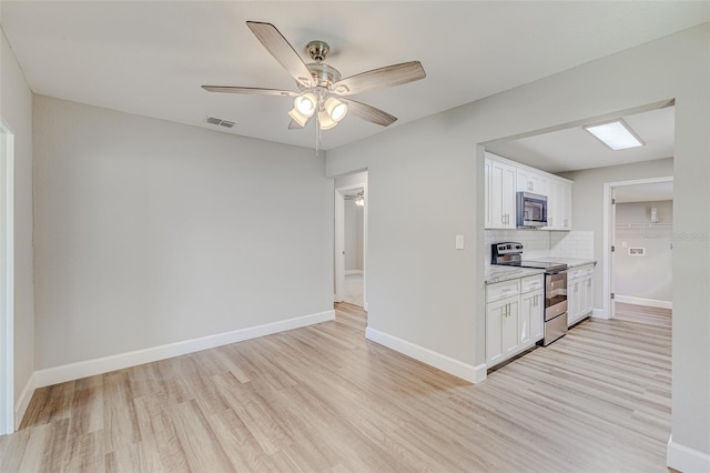 kitchen featuring appliances with stainless steel finishes, decorative backsplash, light hardwood / wood-style floors, white cabinetry, and ceiling fan