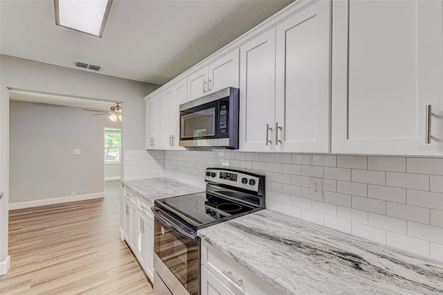 kitchen with white cabinets, light hardwood / wood-style flooring, stainless steel appliances, light stone countertops, and ceiling fan