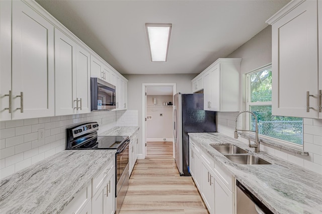 kitchen featuring sink, white cabinetry, light hardwood / wood-style flooring, stainless steel appliances, and light stone countertops