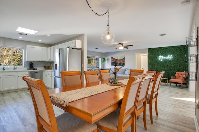 dining space with ceiling fan, sink, and light hardwood / wood-style flooring