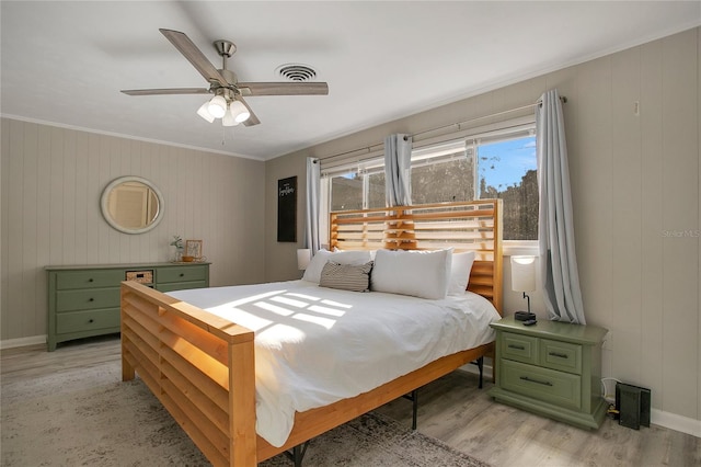 bedroom featuring light wood-type flooring, ceiling fan, and wood walls