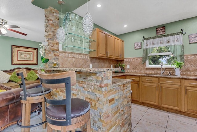 kitchen featuring light tile patterned floors, light stone countertops, ceiling fan, and tasteful backsplash