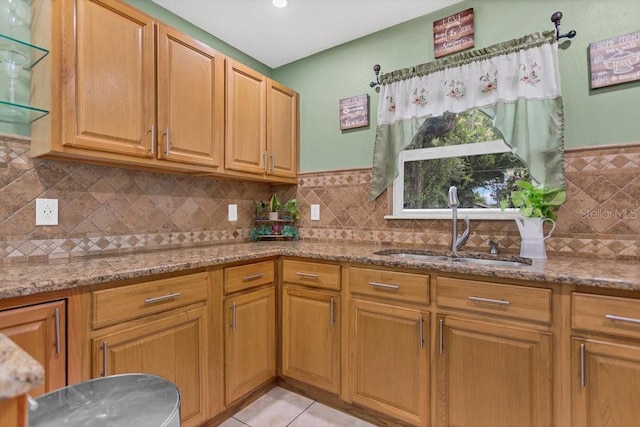 kitchen with light stone countertops, sink, light tile patterned floors, and tasteful backsplash