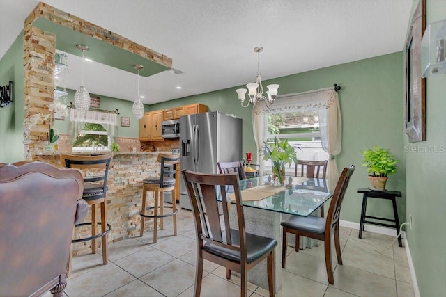 dining area featuring an inviting chandelier, a textured ceiling, and light tile patterned floors