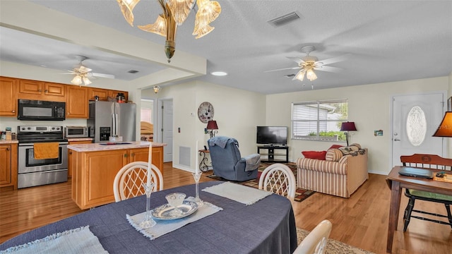 dining room with a textured ceiling, ceiling fan, and light hardwood / wood-style flooring